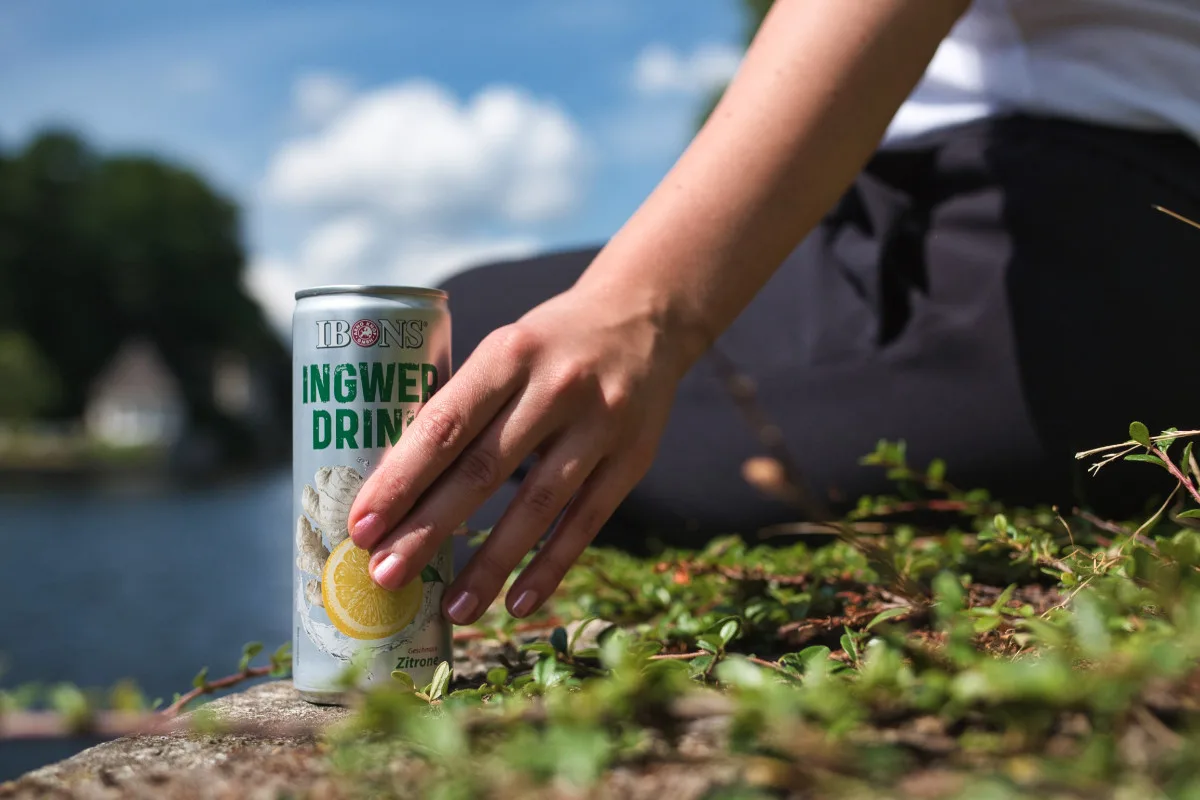 Werbefotografie für Ibons: Hand stellt eine Dose Ingwer-Drink ins Moos