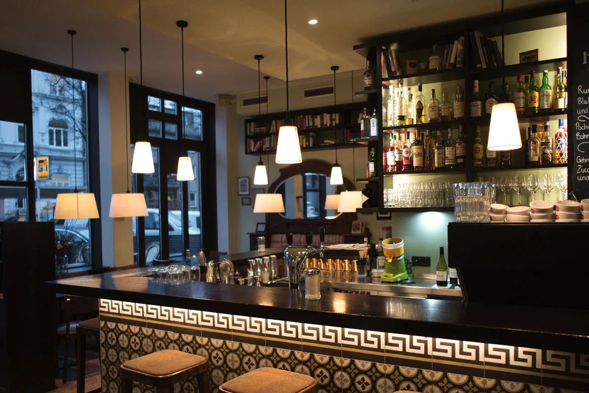 Locationfotografie: Innenraum einer Bar mit Tresen, Hockern und Regal