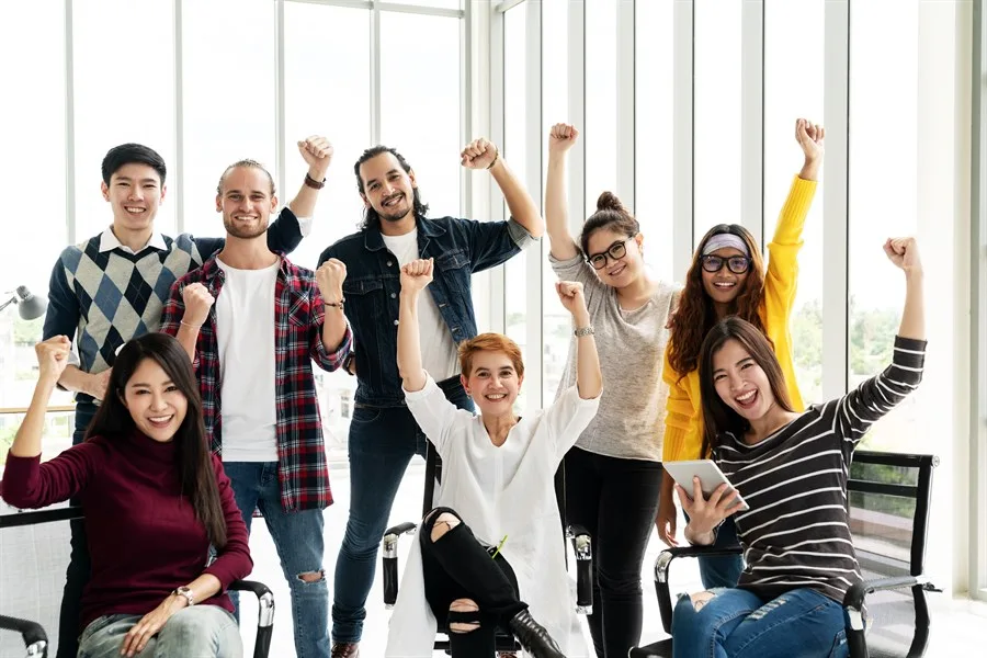 Ein vielfältiges Team jubelt gemeinsam im Büro